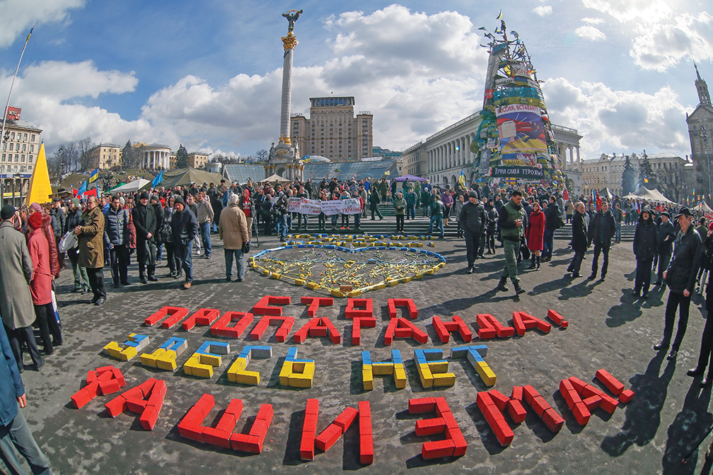 epa04128083 Ukrainians stand around a slogan 'Stop propaganda! There is no a fascism here!', on the Independence Square in Kiev, Ukraine, 16 March 2014. Polling stations opened in Crimea for a referendum about whether the Ukrainian Black Sea region should join Russia. The vote has been widely condemned by Western governments, who call it illegal and have announced sanctions against Russia if it goes ahead. Thousands of unmarked forces, believed to be Russian, have appeared in Crimea after local Moscow-backed authorities asked Russia for protection against 'extremists' in the new Ukrainian leadership. EPA/SERGEY DOLZHENKO
