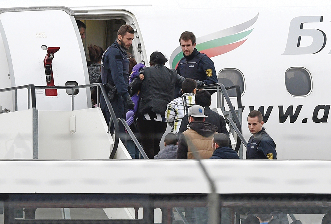 Немецкие полицейские конвоируют мигрантов из Косово, получивших отказ в предоставлении убежища, на самолет в аэропорту Карлсруэ/Баден-Баден в ноябре 2015 г. AFP/GETTY IMAGES
